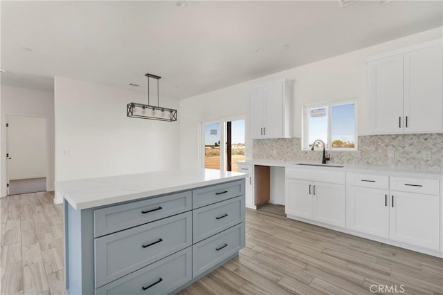 22212 Lone Eagle Rd, Apple Valley, CA 92308 - kitchen with decorative backsplash, white cabinets, a kitchen island, pendant lighting, and light wood-style floors