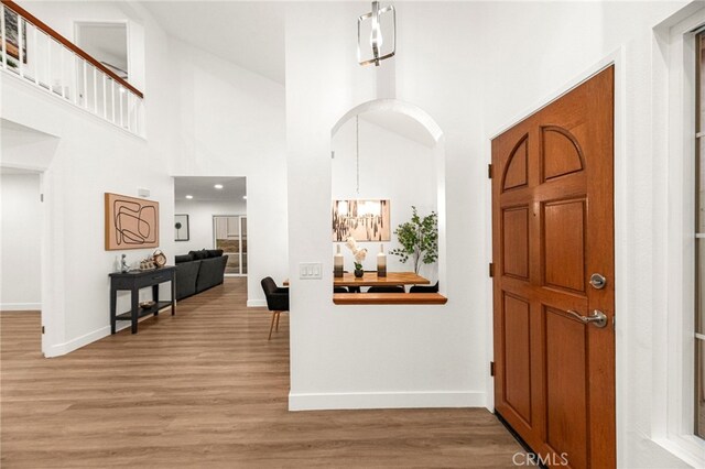 12573 Brickellia St, San Diego, CA 92129 - foyer with a towering ceiling, baseboards, light wood-style floors, arched walkways, and a chandelier