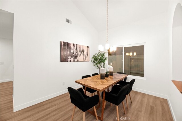 12573 Brickellia St, San Diego, CA 92129 - dining room featuring wood finished floors, a chandelier, baseboards, lofted ceiling, and arched walkways