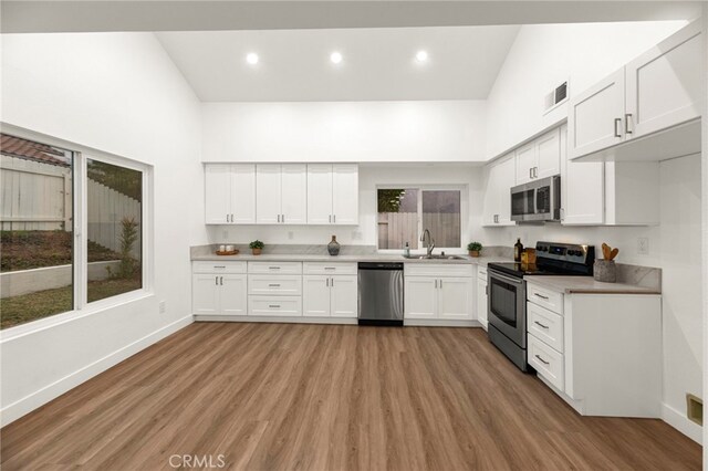 12573 Brickellia St, San Diego, CA 92129 - kitchen featuring stainless steel appliances, a sink, baseboards, a high ceiling, and white cabinets