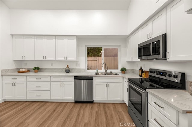 12573 Brickellia St, San Diego, CA 92129 - kitchen featuring appliances with stainless steel finishes, a sink, light wood finished floors, white cabinets, and light stone countertops