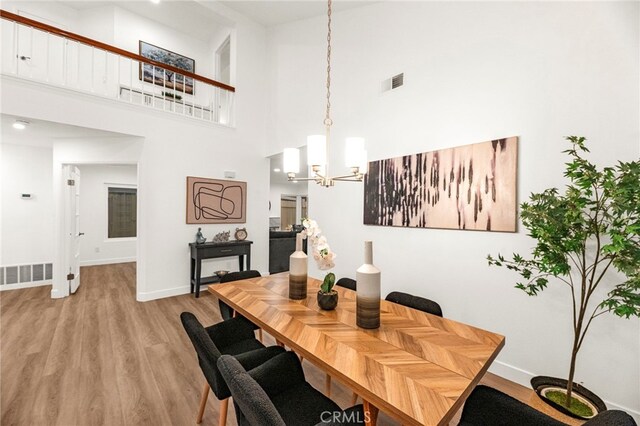 12573 Brickellia St, San Diego, CA 92129 - dining space featuring a chandelier, light wood finished floors, a high ceiling, and baseboards