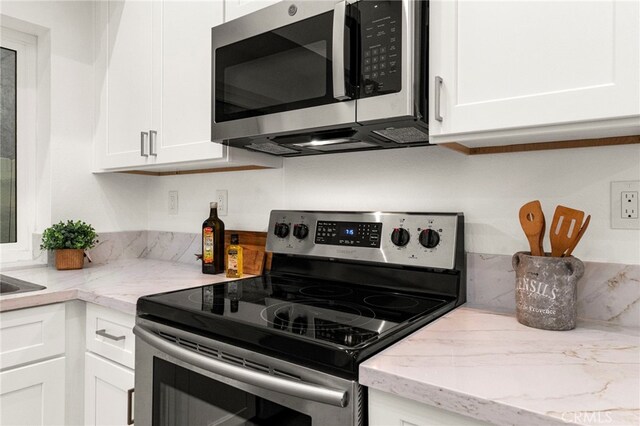 12573 Brickellia St, San Diego, CA 92129 - kitchen featuring appliances with stainless steel finishes, white cabinets, and light stone countertops