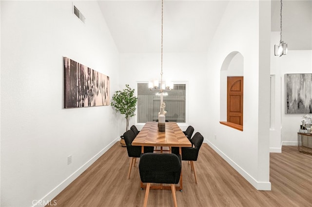 12573 Brickellia St, San Diego, CA 92129 - dining room with high vaulted ceiling, baseboards, light wood-style floors, a chandelier, and arched walkways