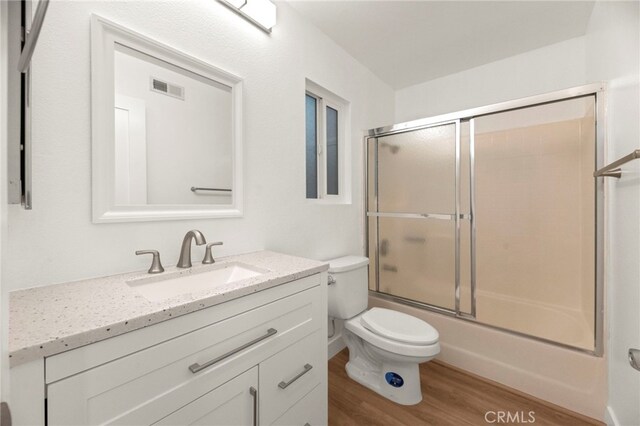 12573 Brickellia St, San Diego, CA 92129 - bathroom featuring toilet, vanity, wood finished floors, and bath / shower combo with glass door
