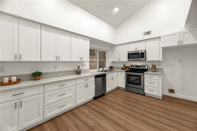 12573 Brickellia St, San Diego, CA 92129 - kitchen with stainless steel appliances, a sink, high vaulted ceiling, white cabinets, and light wood finished floors