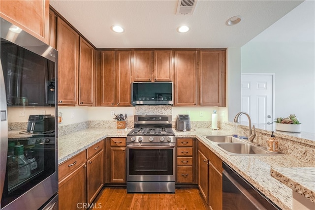 28426 Herrera St, Valencia, CA 91354 - kitchen featuring appliances with stainless steel finishes, a sink, wood finished floors, brown cabinetry, and recessed lighting