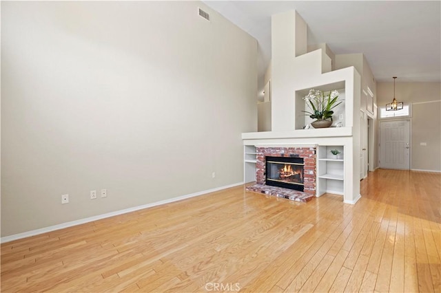 27523 Wellington Ct, Valencia, CA 91354 - unfurnished living room featuring light wood-style floors, baseboards, a chandelier, and a brick fireplace