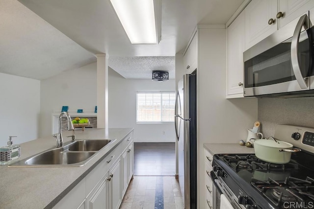 1695 Bubbling Well Dr, San Diego, CA 92154 - kitchen featuring appliances with stainless steel finishes, a sink, white cabinetry, light wood finished floors, and light countertops