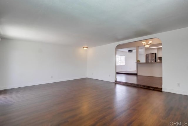 1695 Bubbling Well Dr, San Diego, CA 92154 - unfurnished living room featuring arched walkways, a chandelier, dark wood-style flooring, and baseboards
