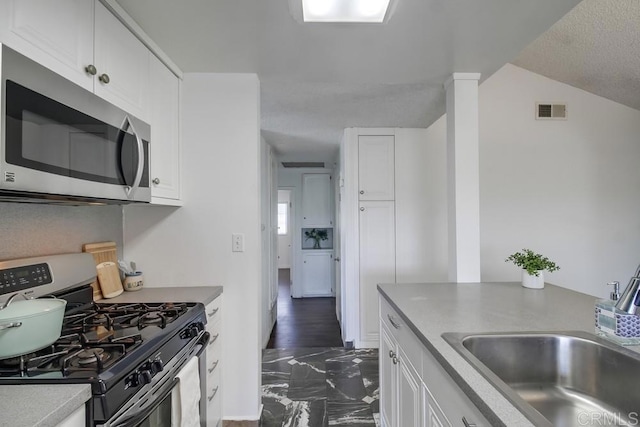 1695 Bubbling Well Dr, San Diego, CA 92154 - kitchen with stainless steel appliances, a sink, white cabinets, and dark marble finish flooring