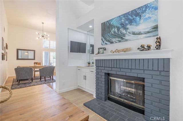 41438 Almond Ave, Palmdale, CA 93551 - living room featuring light wood-style floors, a brick fireplace, baseboards, a chandelier, and a towering ceiling
