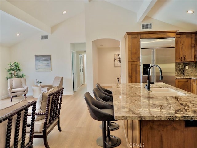 2821 Tucker Ln, Rossmoor, CA 90720 - kitchen featuring stainless steel built in refrigerator, a sink, light wood-style floors, arched walkways, and brown cabinets