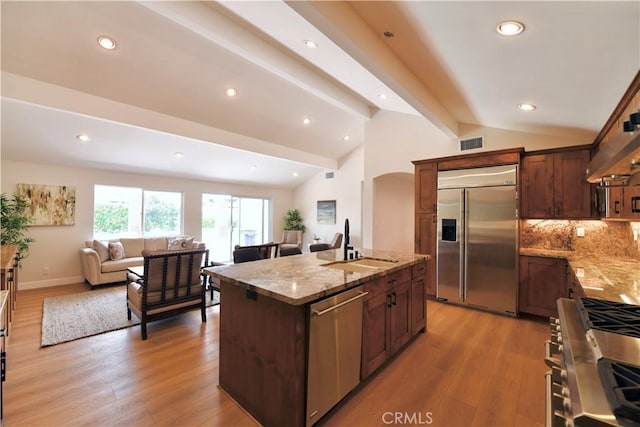 2821 Tucker Ln, Rossmoor, CA 90720 - kitchen with stainless steel appliances, a sink, open floor plan, arched walkways, and light stone countertops