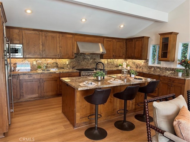 2821 Tucker Ln, Rossmoor, CA 90720 - kitchen with extractor fan, light wood-type flooring, stainless steel microwave, a center island with sink, and a breakfast bar