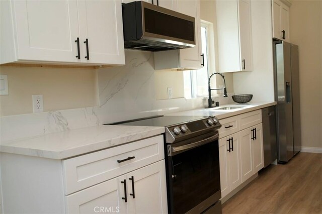 6702 E El Progreso St, Long Beach, CA 90815 - kitchen featuring appliances with stainless steel finishes, a sink, light wood-type flooring, and white cabinets