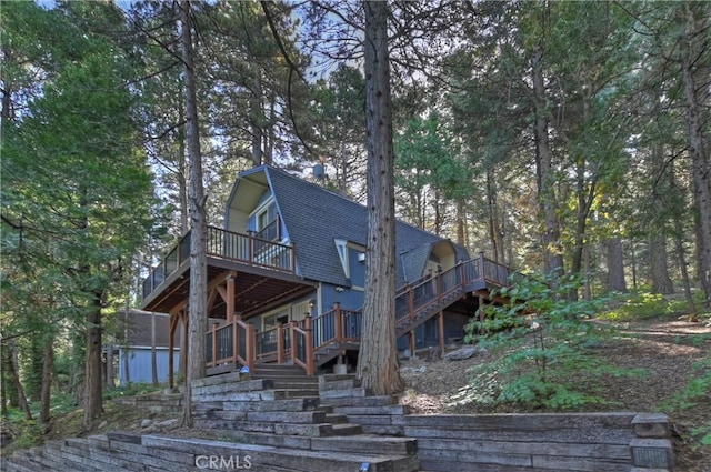 24091 Lakeview Dr, Crestline, CA 92325 - view of front facade with stairway, a shingled roof, a deck, and a gambrel roof