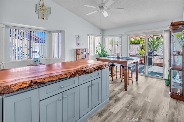 26834 Pinckney Way, Menifee, CA 92586 - kitchen with a textured ceiling, lofted ceiling, a ceiling fan, light wood-style floors, and dark stone counters