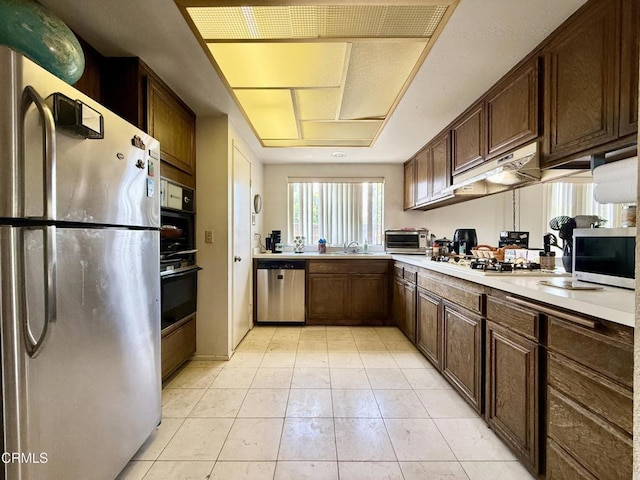 1431 Holly Ave, Oxnard, CA 93036 - kitchen with stainless steel appliances, light countertops, under cabinet range hood, light tile patterned flooring, and dark brown cabinets
