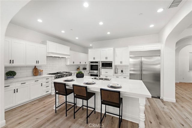 4 Dennis Ln, Ladera Ranch, CA 92694 - kitchen featuring built in appliances, arched walkways, decorative backsplash, white cabinetry, and recessed lighting
