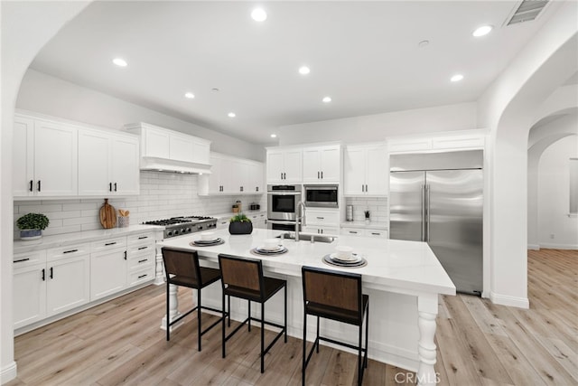 4 Dennis Ln, Ladera Ranch, CA 92694 - kitchen featuring built in appliances, arched walkways, decorative backsplash, white cabinetry, and recessed lighting