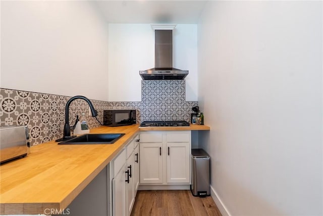 11101 Blix St, Toluca Lake, CA 91602 - kitchen featuring wall chimney range hood, black microwave, gas stovetop, light wood-style floors, and decorative backsplash