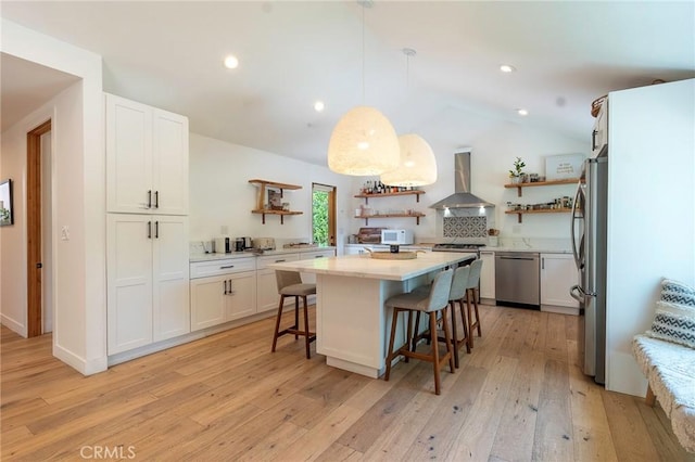 11101 Blix St, Toluca Lake, CA 91602 - kitchen with open shelves, wall chimney exhaust hood, appliances with stainless steel finishes, light wood-type flooring, and a breakfast bar area