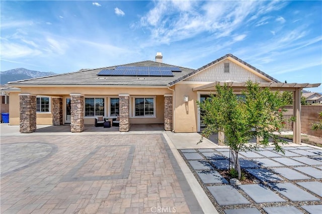 13691 Cobalt Ct, Rancho Cucamonga, CA 91739 - back of property featuring solar panels, stucco siding, a tiled roof, outdoor lounge area, and stone siding