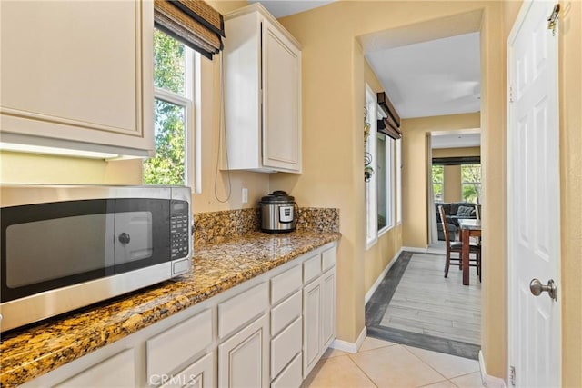 1137 Pamplona Dr, Riverside, CA 92508 - kitchen with stainless steel microwave, baseboards, light stone counters, white cabinetry, and light tile patterned flooring
