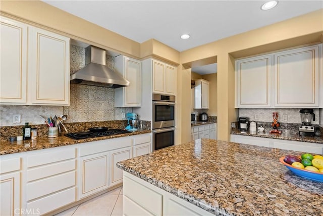 1137 Pamplona Dr, Riverside, CA 92508 - kitchen with wall chimney range hood, black gas cooktop, stainless steel double oven, dark stone countertops, and tasteful backsplash