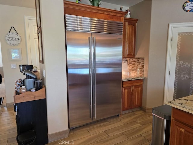 42036 Desert Sage Ave, Lancaster, CA 93536 - kitchen featuring built in refrigerator, brown cabinetry, light stone countertops, and wood tiled floors