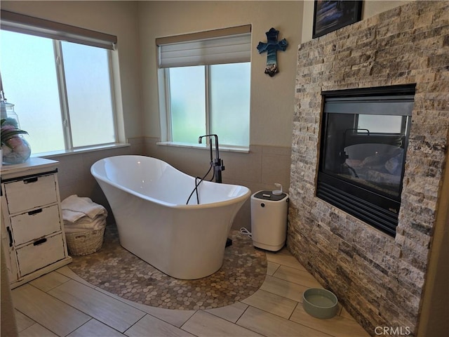 42036 Desert Sage Ave, Lancaster, CA 93536 - full bathroom with tile walls, a soaking tub, wainscoting, and a fireplace