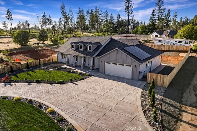 5539 Erin Way, Paradise, CA 95969 - view of front of property featuring board and batten siding, an attached garage, roof mounted solar panels, driveway, and covered porch