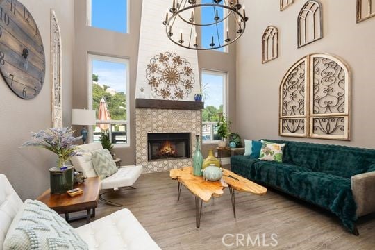 41350 Calle Bandido, Murrieta, CA 92562 - living room with plenty of natural light, wood finished floors, a chandelier, a fireplace, and a high ceiling