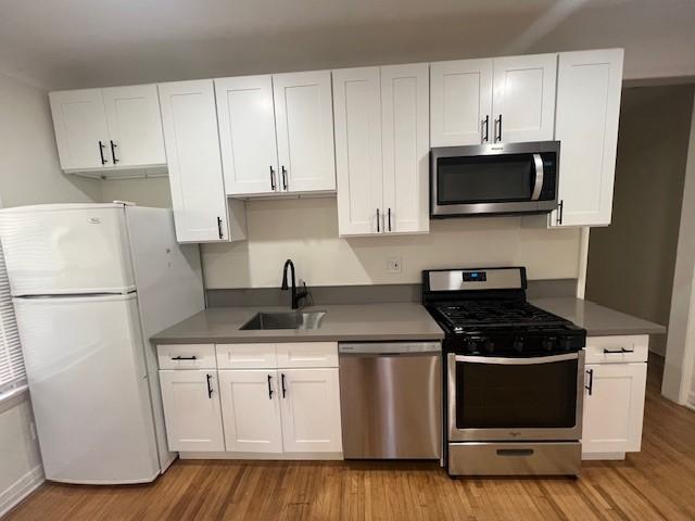 3320 E 8th St, Long Beach, CA 90804 - kitchen with appliances with stainless steel finishes, a sink, white cabinets, and light wood-style floors