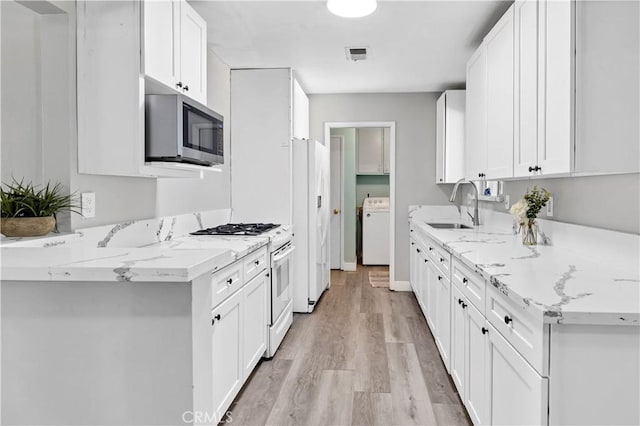 40632 Lela May Ave, Hemet, CA 92544 - kitchen with white appliances, washer / dryer, a sink, light wood-type flooring, and white cabinets