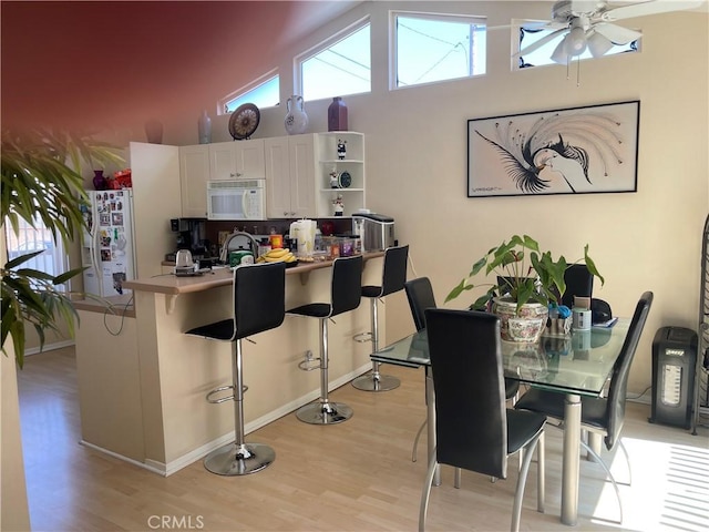 927 W 6th St, San Pedro, CA 90731 - kitchen featuring white appliances, light wood-type flooring, white cabinets, a kitchen bar, and a towering ceiling