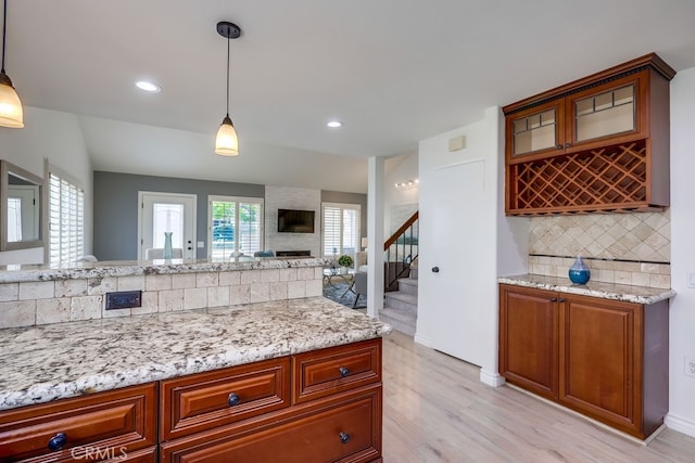 7712 Rockybrook Way, Stanton, CA 90680 - kitchen featuring decorative backsplash, light wood-type flooring, light stone countertops, decorative light fixtures, and glass insert cabinets