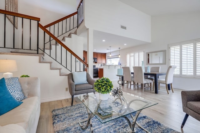 7712 Rockybrook Way, Stanton, CA 90680 - living room with stairs, light wood-style flooring, a high ceiling, baseboards, and recessed lighting