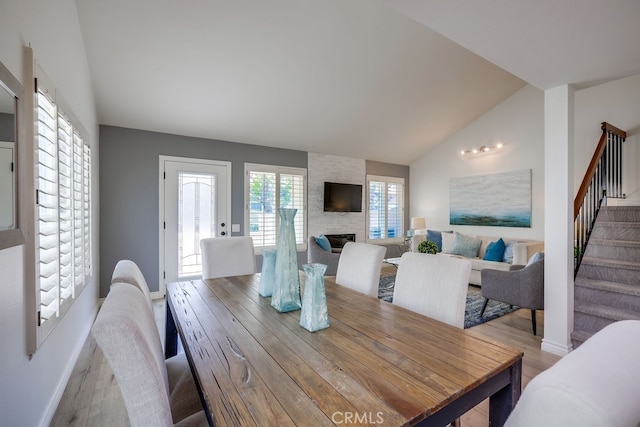 7712 Rockybrook Way, Stanton, CA 90680 - dining area featuring lofted ceiling, wood finished floors, stairway, a stone fireplace, and baseboards