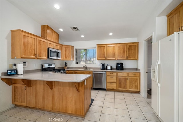 9552 Palm Dr, Desert Hot Springs, CA 92240 - kitchen with appliances with stainless steel finishes, a peninsula, light tile patterned floors, light countertops, and a breakfast bar area