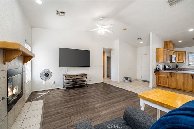 9552 Palm Dr, Desert Hot Springs, CA 92240 - living room with a tiled fireplace, light wood-type flooring, lofted ceiling, ceiling fan, and recessed lighting