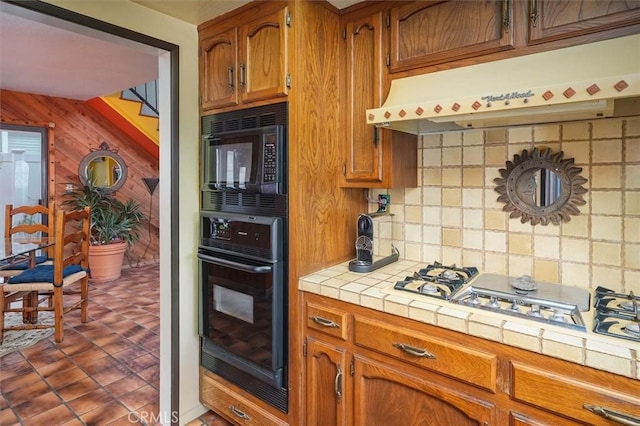537 3rd St, Manhattan Beach, CA 90266 - kitchen featuring black appliances, range hood, tile countertops, backsplash, and brown cabinets