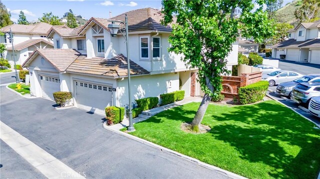 5847 E Rocking Horse Way Unit 21, Orange, CA 92869 - view of front of property with stucco siding, a tiled roof, asphalt driveway, a front lawn, and a residential view