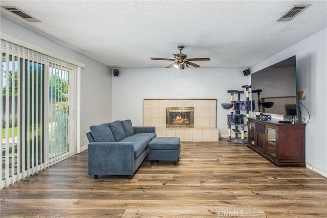 1210 3rd St, Calimesa, CA 92320 - living room with wood finished floors, a textured ceiling, a ceiling fan, and a tile fireplace