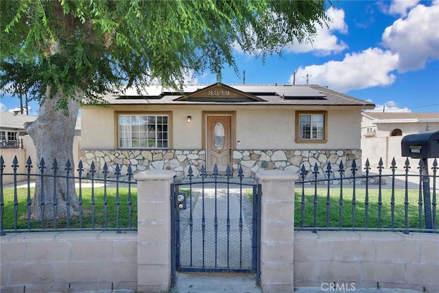3879 Big Dalton Ave, Baldwin Park, CA 91706 - bungalow-style house featuring stone siding, stucco siding, a fenced front yard, and roof mounted solar panels