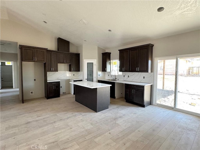 14549 Live Oak St, Hesperia, CA 92345 - kitchen with decorative backsplash, light wood finished floors, a kitchen island, dark brown cabinets, and vaulted ceiling