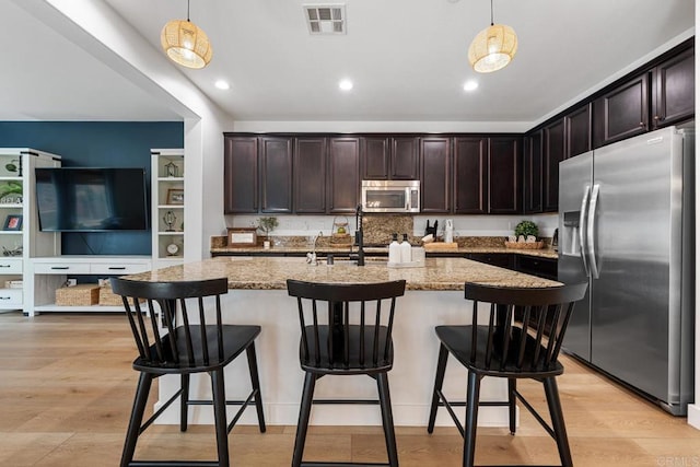 25444 Red Hawk Rd, Corona, CA 92883 - kitchen with appliances with stainless steel finishes, dark brown cabinetry, light stone counters, decorative light fixtures, and recessed lighting