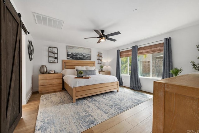 25444 Red Hawk Rd, Corona, CA 92883 - bedroom with a barn door, light wood-style flooring, ceiling fan, and baseboards