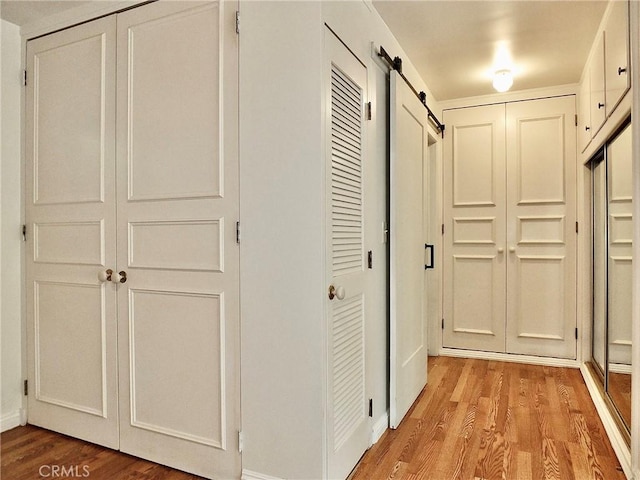 5510 E La Pasada St E, Long Beach, CA 90815 - hall with light wood-type flooring, a barn door, and baseboards